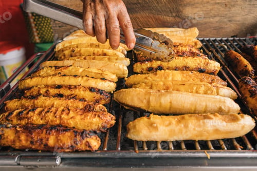 Preview: Hands of an unrecognizable person, grilling plantains at a street market stall