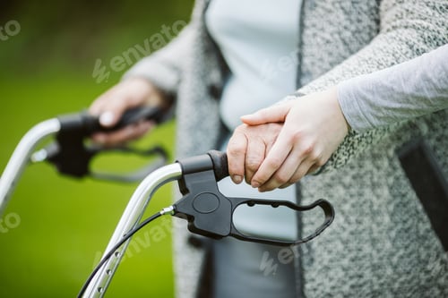 Vorschau: Seniorin mit Gehhilfe beim Spaziergang im Park eines modernen Pflegeheims