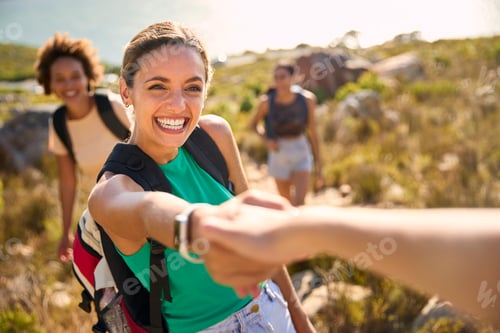 Preview: Group Of Female Friends With Backpacks Helping Each Other On Hike In Countryside On Coastal Path