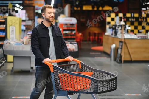 Preview: Handsome man buying some healthy food and drink in modern supermarket or grocery store