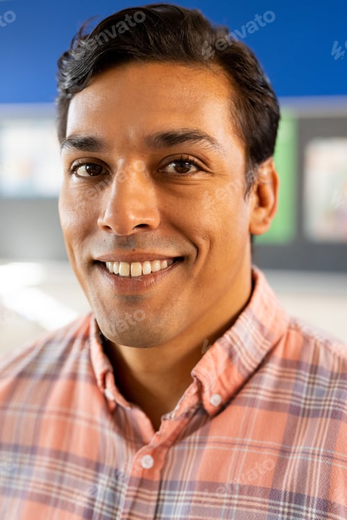 Preview: Portrait of happy biracial male teacher with tablet in classroom at elementary school