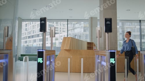 Preview: Woman opening automatic gates using smartwatch in modern office building.