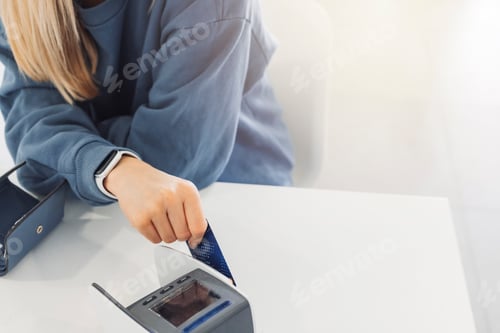 Preview: A woman with long blonde hair is smiling while using a card reader at a table. She is wearing a blue