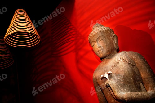 Preview: Statue of Buddha against red wall.