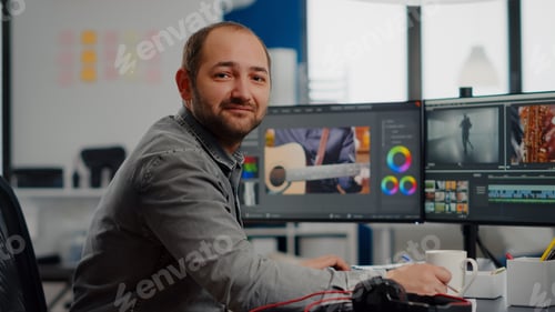 Preview: Videographer smiling at camera working on computer