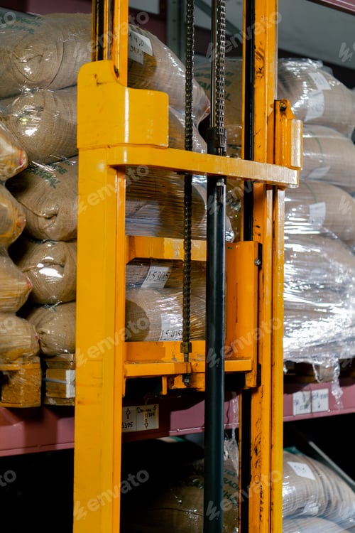Preview: close up A worker at coffee factory uses a yellow lifting fork to lift and insert forks into pallets