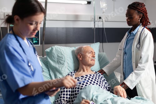 Preview: African doctor in hospital room discussing with sick senior man