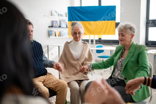 Preview: Group of seniors holding hands and praying for Ukraine together in church community center
