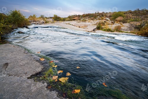 Preview: A small shining stream flows among smooth wet and dark stones
