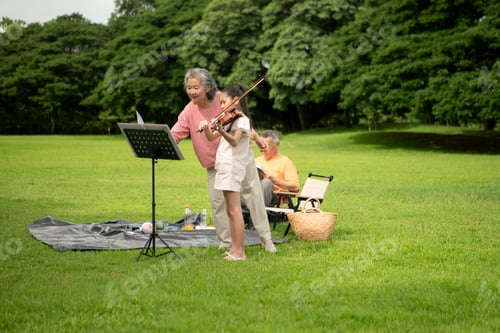 Preview: Happy Asian grandparents enjoying a picnic with their granddaughter in a green park
