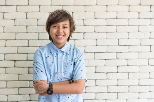 Preview: secondary school boy student standing in front of classroom smiling and looking at camera