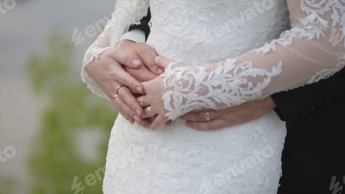 Preview: Bride holds a wedding bouquet in hands, the groom hugs her from behind. groom hugging the bride from