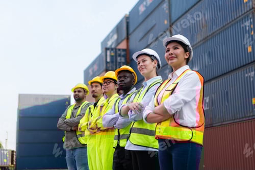 Preview: Group of worker wearing safety helmet and reflective vest standing in front of containers.