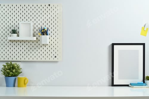 Preview: Blank photo frame, houseplant and coffee cup on white table with pegboard on wall