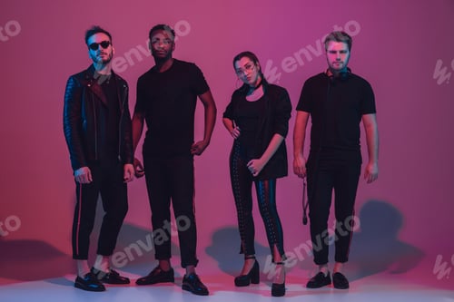 Preview: Group of young multiethnic musicians created band, dancing in neon light on pink background