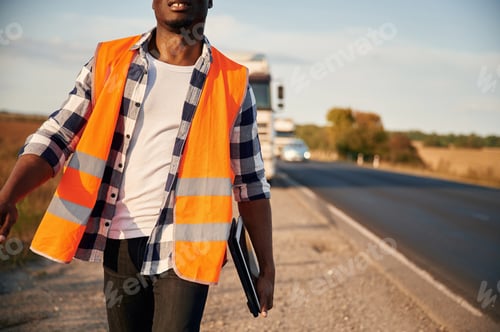 Preview: Modern technology concept. With tablet. Black man is standing on the road with truck on it