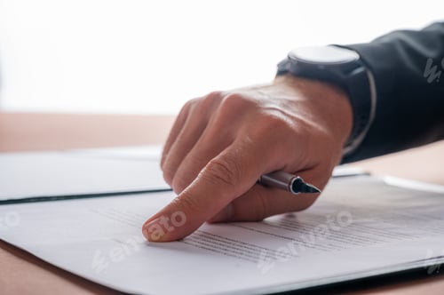 Preview: Hand of a businessman holding an ink pen pointing to the top part of a contract or document