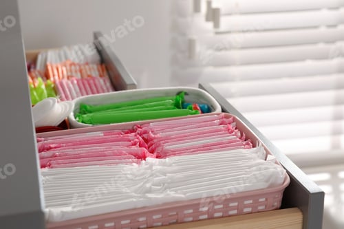 Preview: Open cabinet drawer with menstrual pads, tampons and pantyliners indoors, closeup