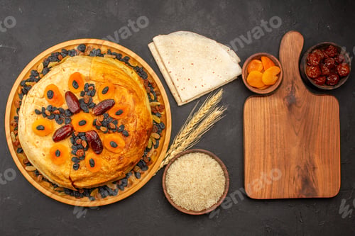 Preview: top view shakh plov delicious rice meal cooked inside round dough with raisins on a grey background