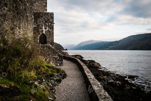 Preview: Castle in wall overlooking a loch with mountains in the distance.