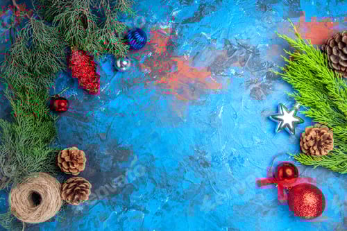 Preview: top view pine tree branches with pinecones and colorful xmas tree toys straw thread on blue-red