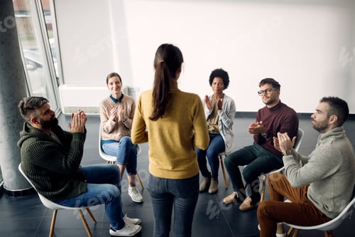 Preview: Group therapy attenders applauding to one of the participant during the meeting.