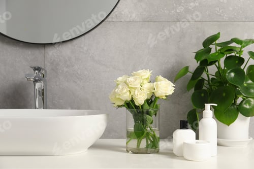 Preview: Beautiful roses, houseplant and bath accessories near sink in bathroom