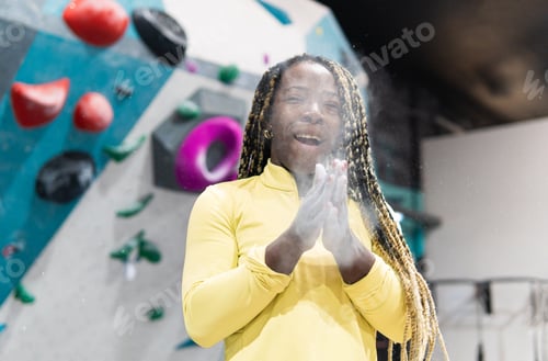 Preview: Woman clapping hands with chalk before bouldering