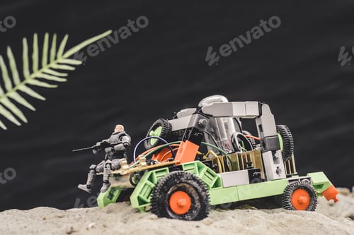 Preview: toy soldier with gun sitting on car on sand dune on black background