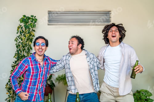 Preview: Three latin friends celebrating, drinking beer and having fun at home