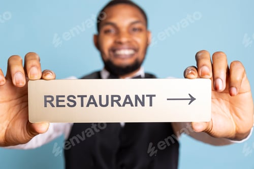 Preview: Hotel porter presenting the direction to the restaurant with a pointer