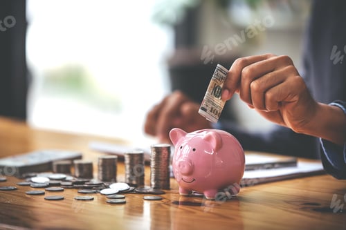 Preview: businessman holding a coin in a piggy bank On a table with sunlight. Money Saving Ideas for Financia