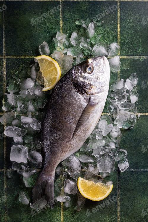 Preview: Fresh fish dorado with lemon on ice