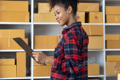 Preview: African woman starting an online shopping business from home is preparing packages to deliver