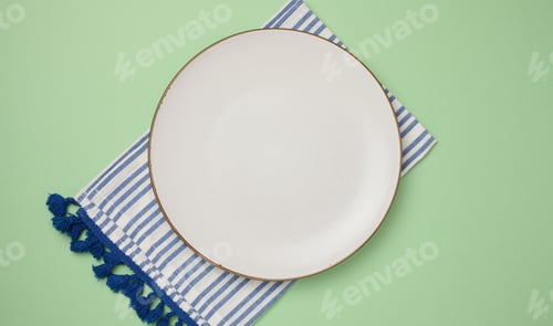 Preview: Empty round ceramic plate and kitchen towel on green background