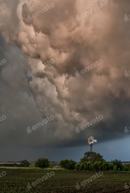 Preview: Dark storm clouds looming over a windmill and field.