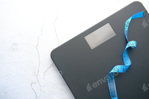 Preview: a tape measure and Bathroom scale on wooden floor.
