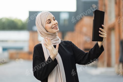 Preview: Portrait of smiling happy beautiful muslim woman relaxing using digital tablet.