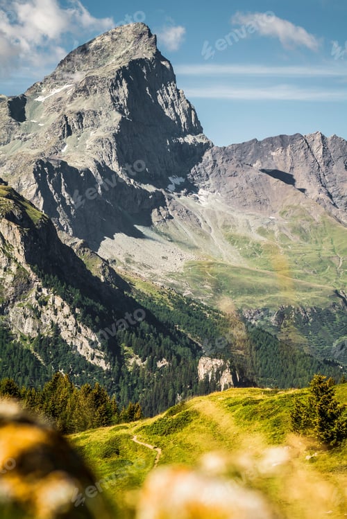 Preview: Rocky mountains over grassy landscape