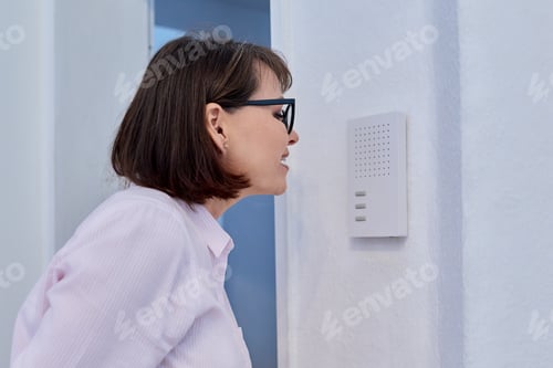 Preview: Woman using intercom inside the house, closeup
