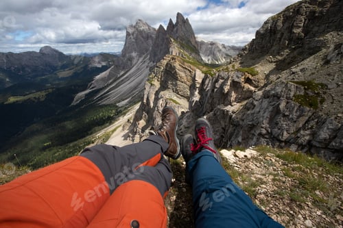 Preview: Trekking boots of a hiker couple while sitting on top of a mountain in Seceda, Dolomites, Italy