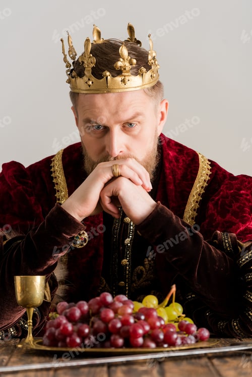 Preview: thoughtful king with crown sitting at table isolated on grey