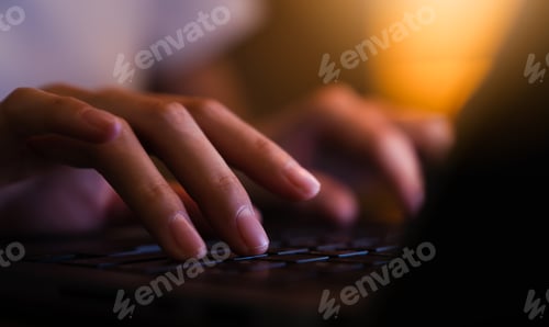 Preview: Hand using laptop and hand typing on the computer keyboard in the office at night