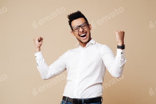 Preview: Afro young man celebrating victory on beige background