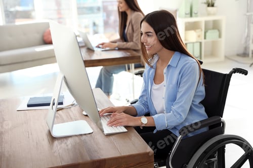 Preview: Young woman in wheelchair using computer at workplace
