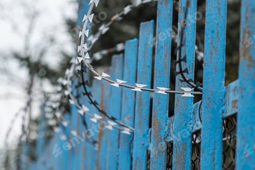 Preview: A blue fence with barbed wire near prison or mental hospital