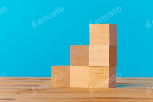Preview: Stacked wooden blocks on wooden desk against blue background