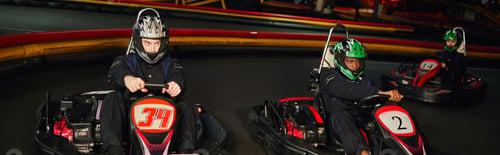 Preview: focused multicultural go cart racers driving on indoor circuit, speed racing and motorsport, banner