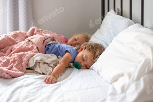 Preview: Two little girls napping on a big white bed