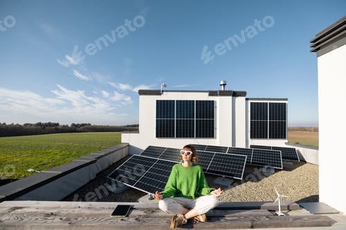 Preview: Woman meditates on rooftop of her house with solar power plant on background